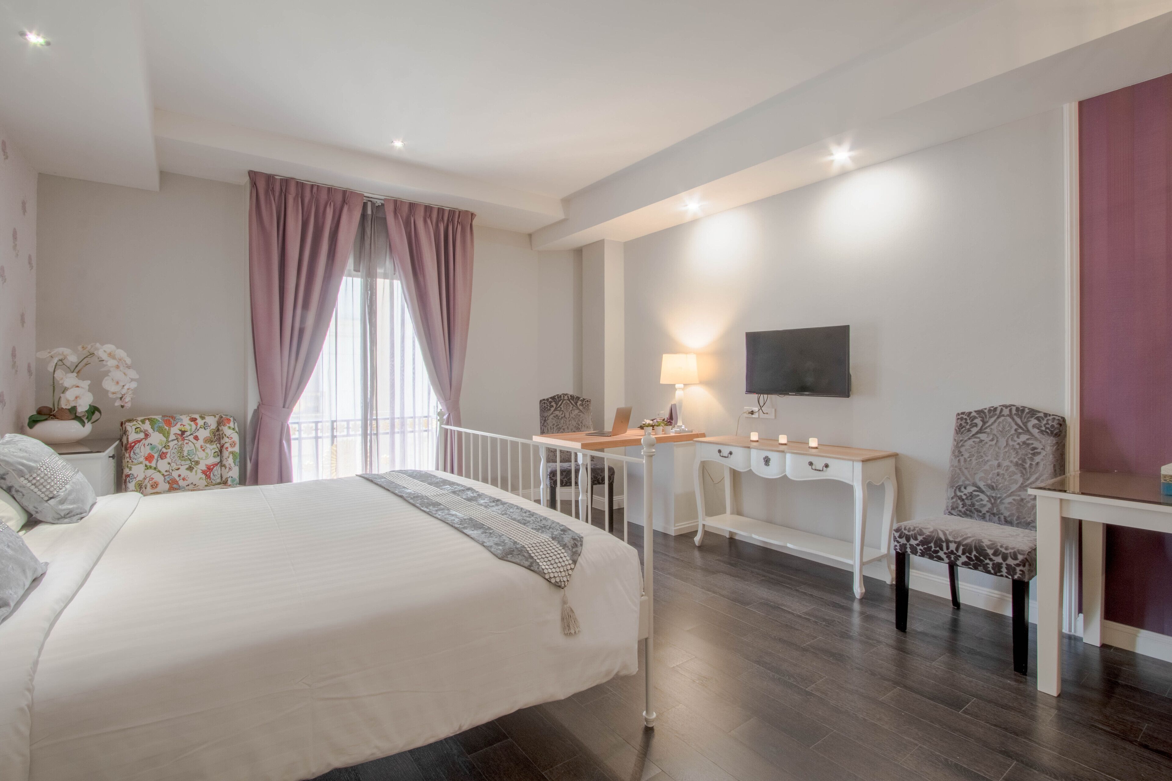 Un dormitorio con una cama grande, un escritorio, una silla y un televisor.