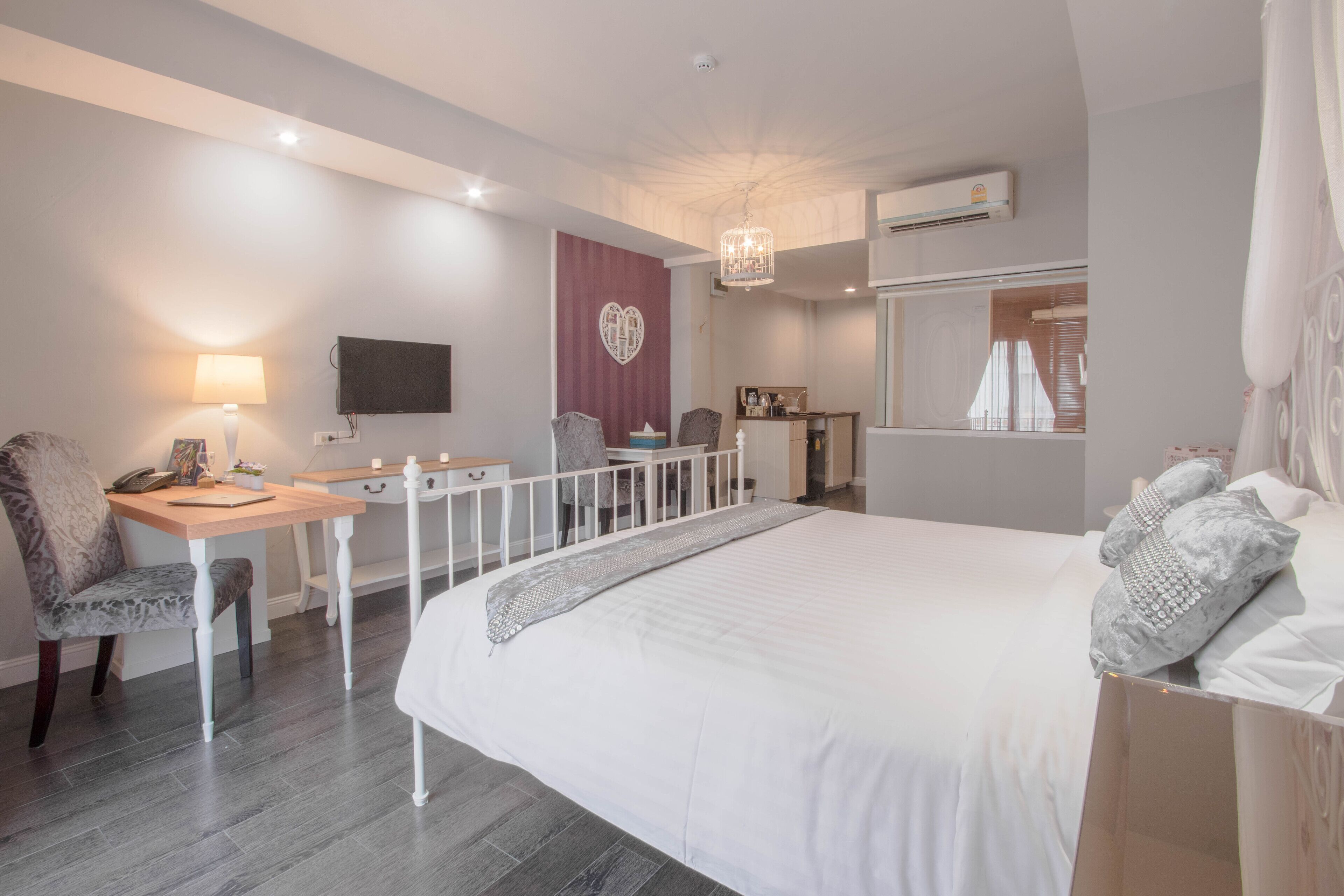 A modern hotel room with a large bed, a desk with a chair, a television, and a wardrobe.