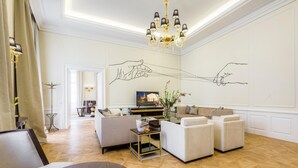 A spacious living room with a modern chandelier, a sofa set, and a decorative wall with line art. - Residence Wollzeile (Vienna)