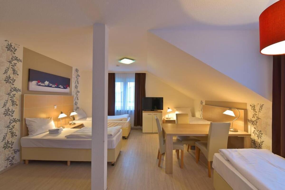 A hotel room with two beds, a desk, and a television.