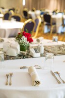A table set for dining with a rolled napkin, cutlery, and a small vase with flowers.