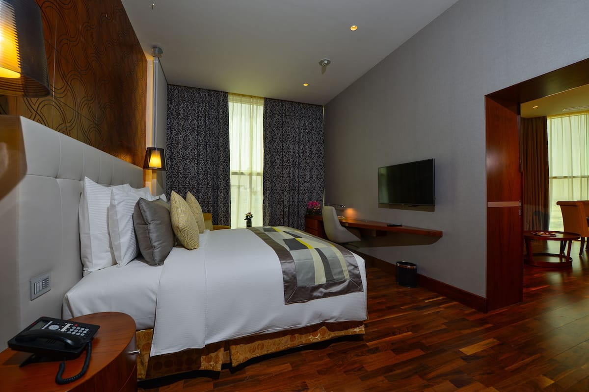 Een hotelkamer met een groot bed, een bureau, een stoel, een televisie en een telefoon.
