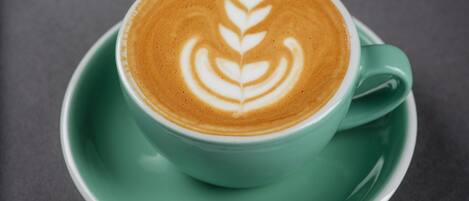A cup of coffee with latte art on a green saucer.