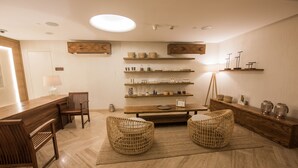 A modern, minimalist room with a wooden dining table, two wicker chairs, and shelves with various items. - The Avenue Hotel (Doha)