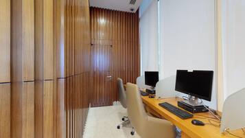 Una oficina moderna con un panel de listones de madera, un escritorio con dos monitores, un teclado y una silla.