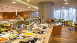 A buffet area with multiple food stations, a central serving counter, and seating arrangements. - The Avenue Hotel (Doha)