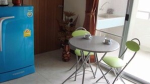 A compact kitchen with a blue refrigerator, a small dining table with two chairs, and a potted plant. - Cosy Place Hatyai (Hat Yai)