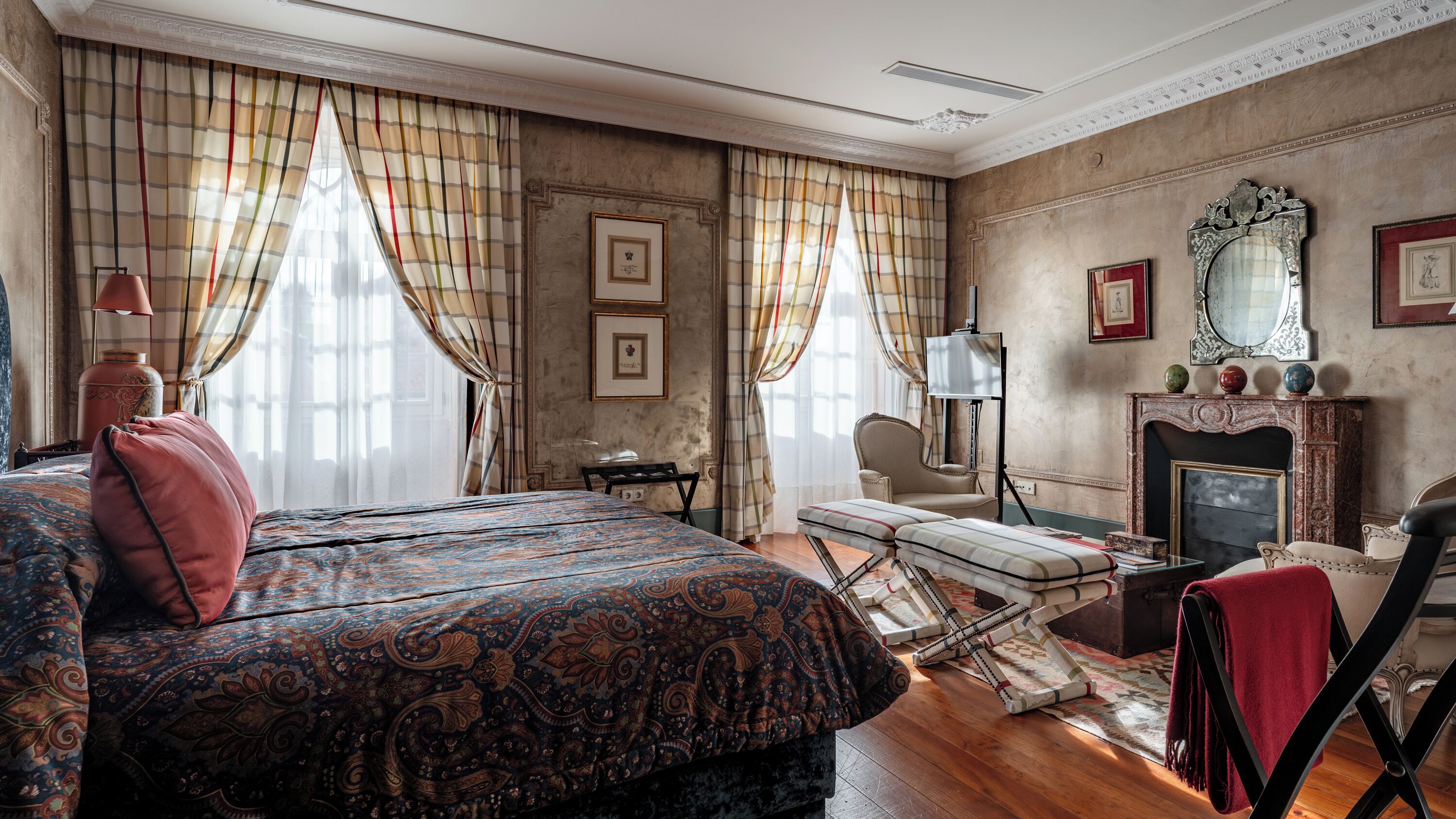 A traditional room with a bed, a fireplace, and a chair.