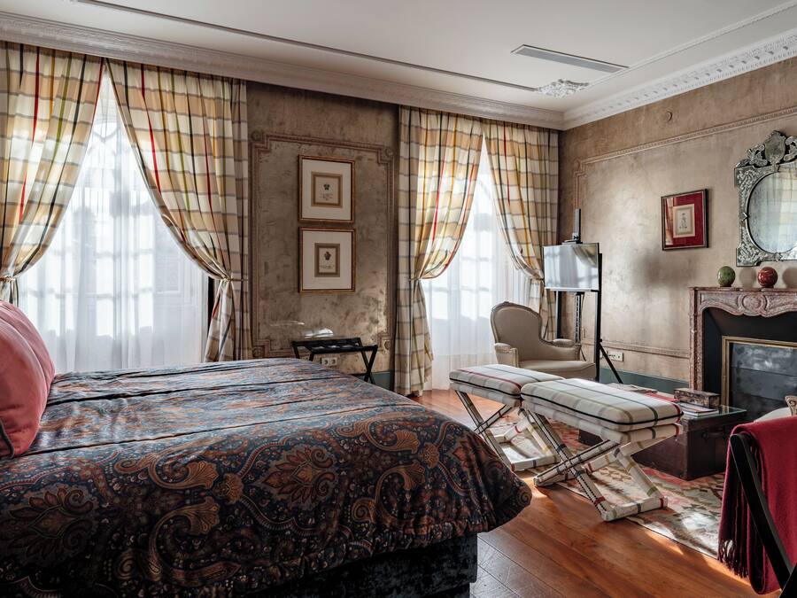 A traditional room with a bed, a fireplace, and a chair.