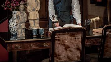 A wooden desk with a vase of flowers, a statue, and a book.