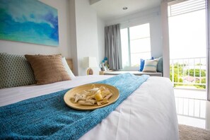 Ein Hotelzimmer mit einem großen Bett, einem Balkon mit Blick und einem Gemälde an der Wand.