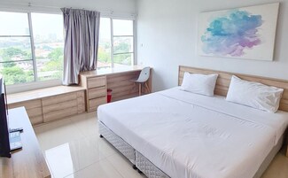 A modern hotel room with a large bed, a desk with a chair, a window with curtains, and a city view.