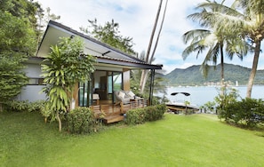 A modern house with a deck overlooking a body of water and mountains.