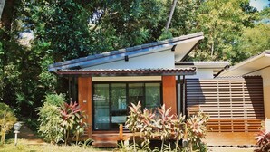 A modern house with a large glass door, surrounded by lush greenery and a small porch. - Resolution Resort (Ko Chang)