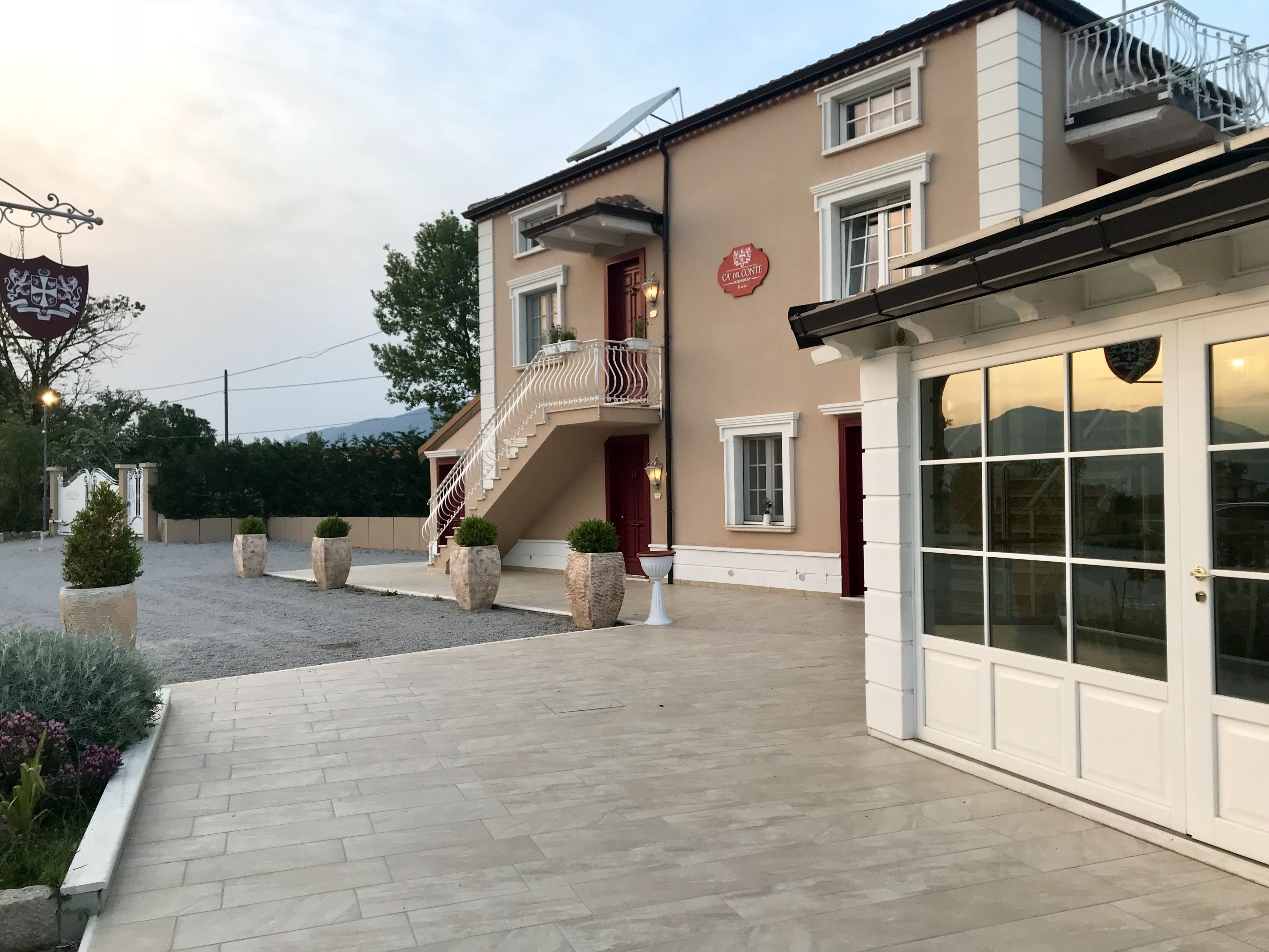 Un edificio con fachada color beige, una puerta roja y un cartel que dice "CA DE CONTE".