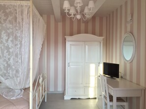 A bedroom with a bed, a wardrobe, a desk, a television, and a mirror.