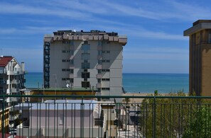 Un immeuble à plusieurs étages doté de balcons donnant sur une plage.