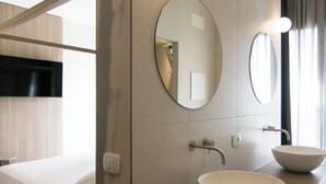 A modern hotel room with a bunk bed, a wooden vanity with a large bowl sink, and two round mirrors. - Hotel Hollywood (Rimini)