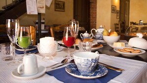 A dining table set with various dishes, glasses, and utensils, indicating a meal setting in a room with a staircase and a brick wall. - Casa Del Grande Vecchio (Airasca)
