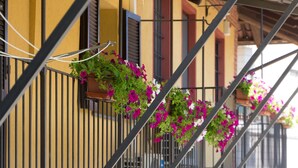 A balcony with hanging flower baskets and a metal railing. - Casa Del Grande Vecchio (Airasca)