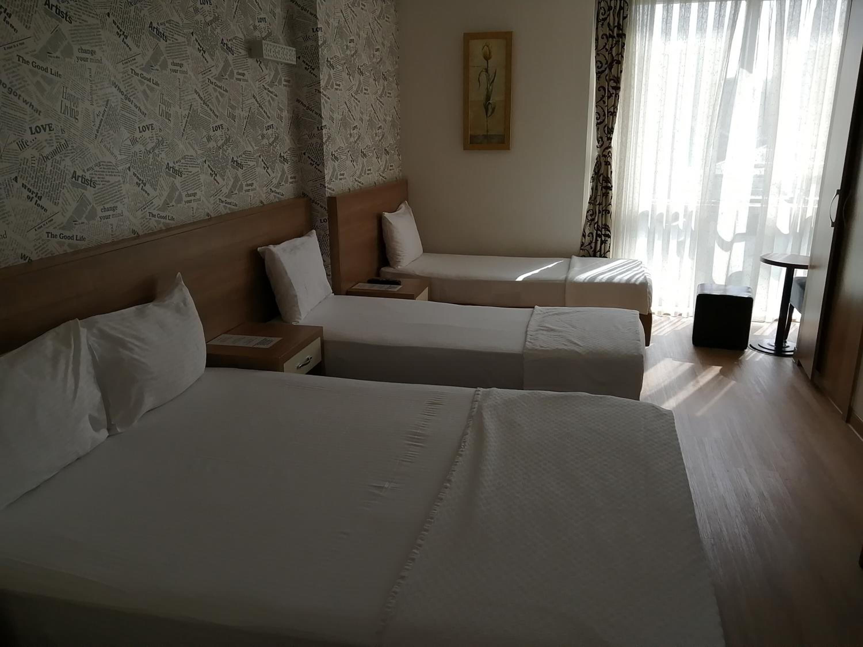 Ein Hotelzimmer mit zwei Betten, einem Holzkopfstück, einem kleinen Tisch und einem Bild an der Wand.