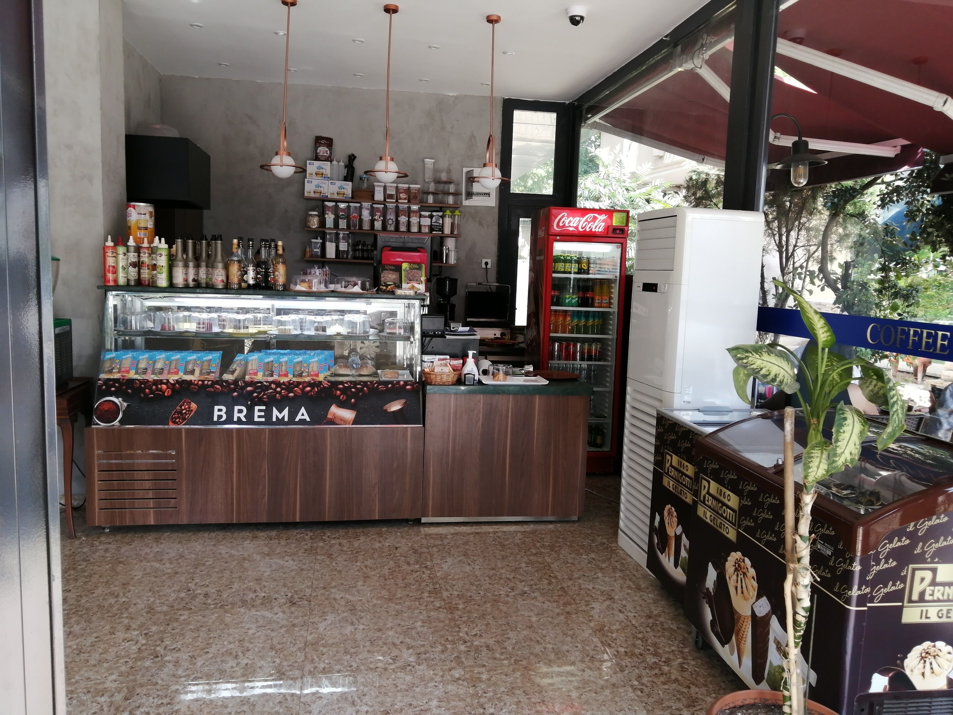Een café interieur met een BREMA display, een Coca-Cola koelkast en een display voor gelato.