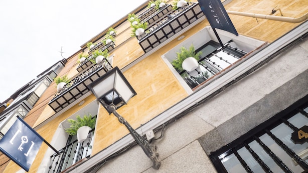 A building with multiple balconies, some with plants and outdoor lighting fixtures. - Oriente Suites (Madrid)