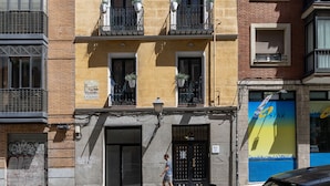 A multi-story building with balconies, a storefront, and parked cars. - Oriente Suites (Madrid)