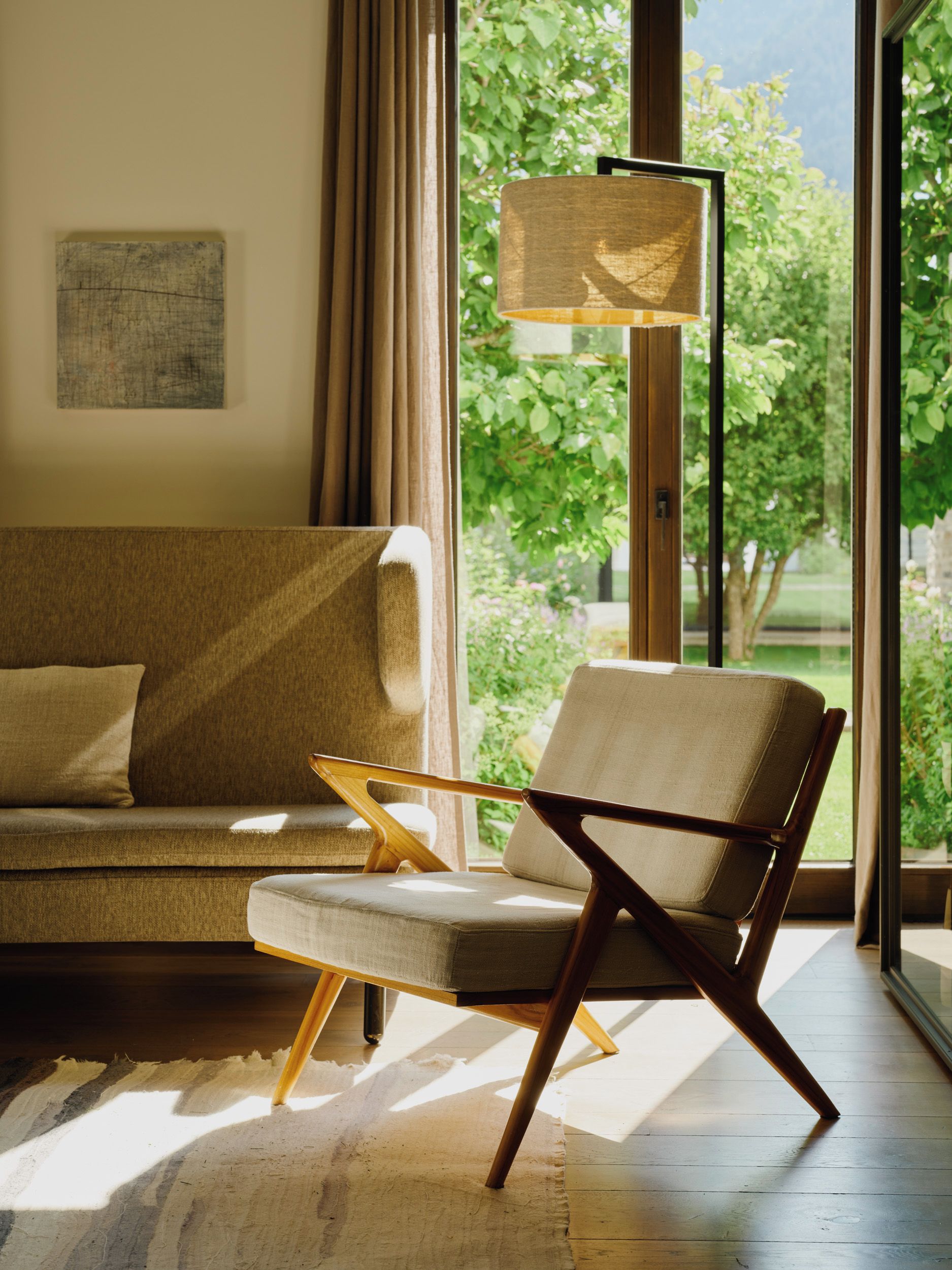 A modern living room with a sofa, a wooden chair, and a floor lamp.