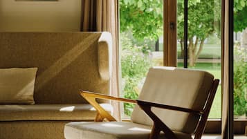 A modern living room with a sofa, a wooden chair, and a floor lamp.