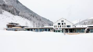 A modern hotel with a large central building and smaller structures, surrounded by snow-covered mountains.