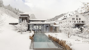 A modern building with a glass facade, surrounded by snow-covered trees and a clear sky. - Wiesergut (Saalbach-Hinterglemm)