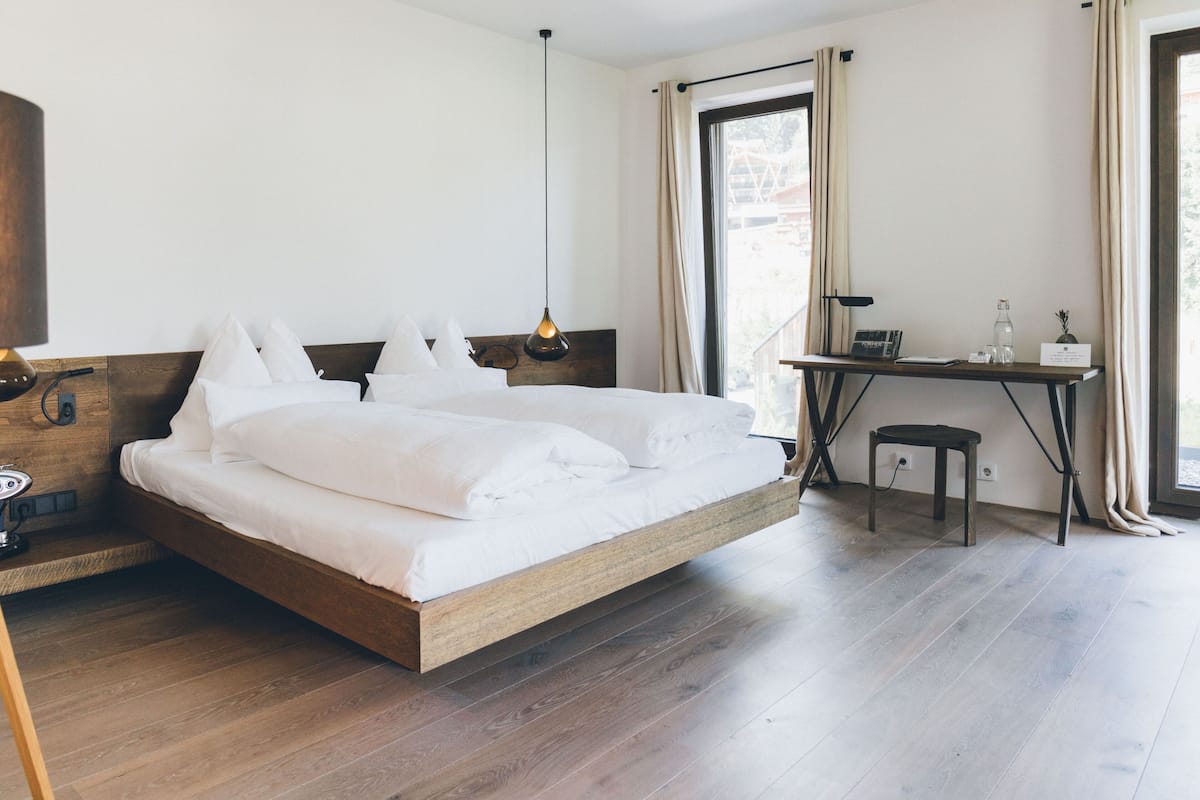A modern bedroom with a wooden bed, a desk, and a hanging light fixture.