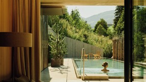 Un interior moderno con piscina, mobiliario exterior y vistas a un paisaje natural.