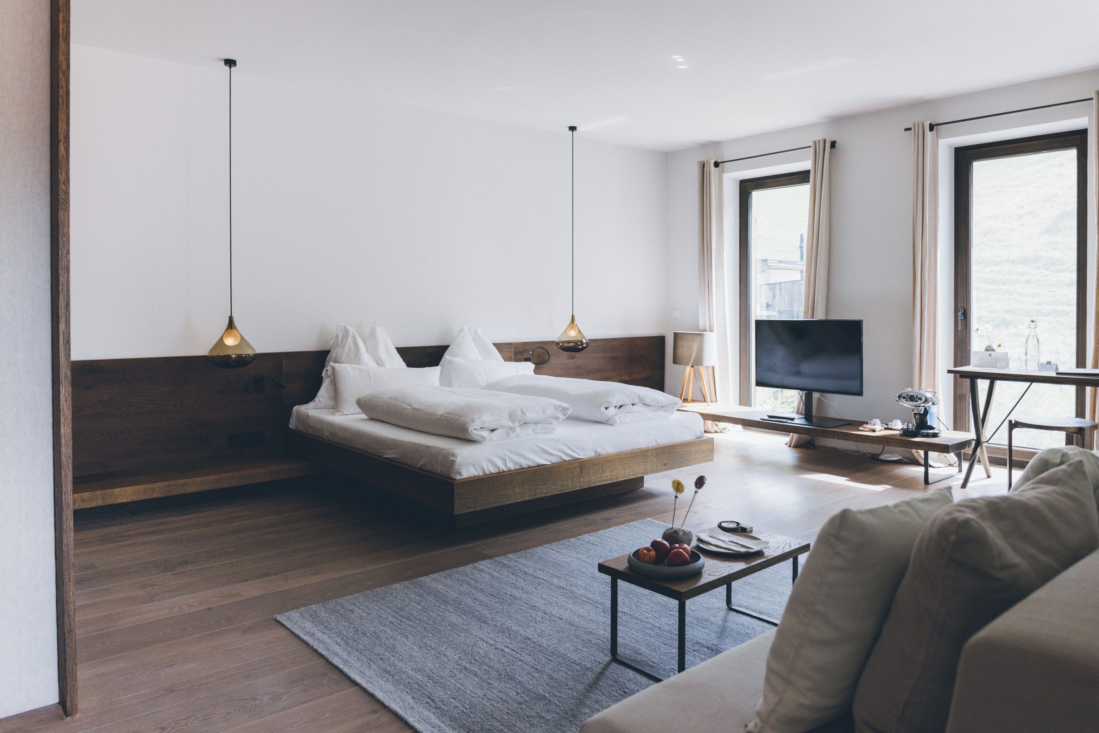 Una habitación de hotel moderna con cama, escritorio, televisión y vistas al exterior.
