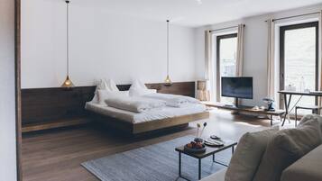 Una habitación de hotel moderna con cama, escritorio, televisión y vistas al exterior.