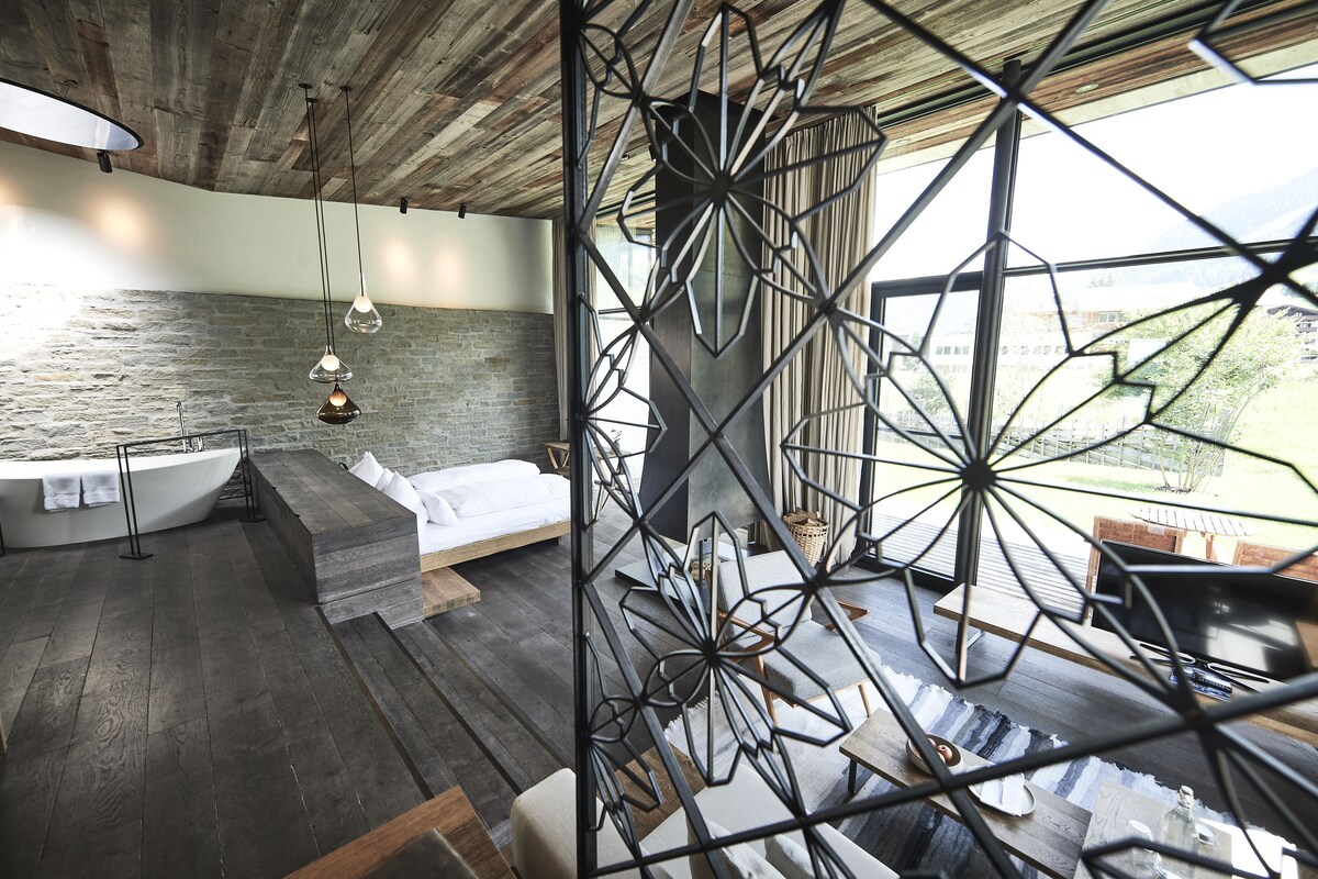 A modern room with a stone wall, a wooden ceiling, and a geometric metal partition.