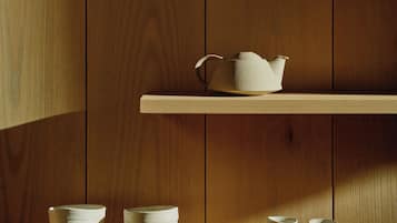 A wooden interior with two shelves, one holding a teapot and the other stacked bowls.