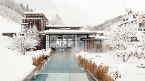 Un edificio moderno con fachada de vidrio, piscina y alrededores nevados.