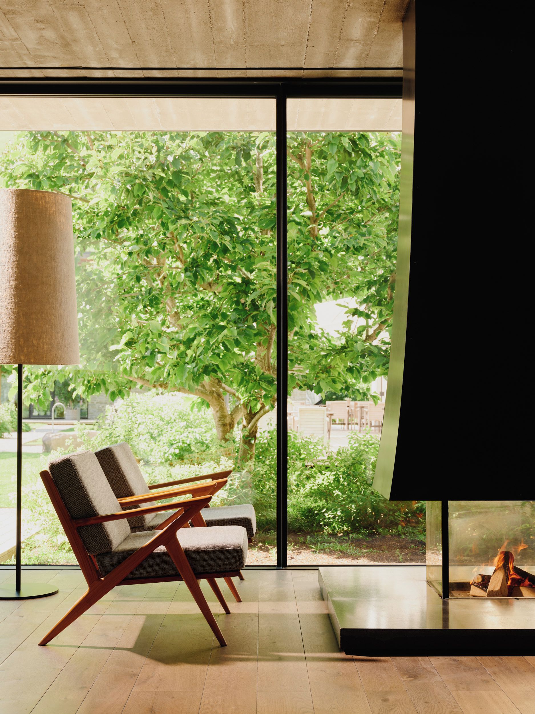 Un salon moderne avec une grande fenêtre, un canapé, une lampe sur pied et une cheminée.