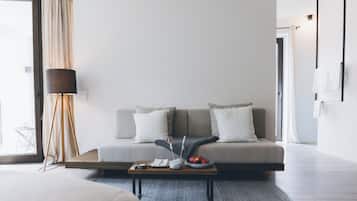 A modern living room with a sofa, a coffee table with fruits, a lamp, and a view of the outdoors.