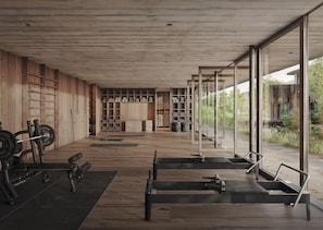 A modern gym with wooden flooring, weightlifting equipment, and large windows offering views of the outdoors. - Wiesergut (Saalbach-Hinterglemm)