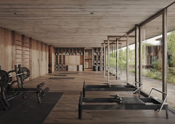 A modern gym with wooden flooring, weightlifting equipment, and large windows offering views of the outdoors. - Wiesergut (Saalbach-Hinterglemm)