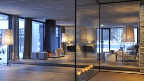 A modern interior with large windows, a stone accent wall, and contemporary furniture. - Wiesergut (Saalbach-Hinterglemm)