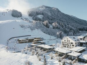 A snow-covered mountain resort with modern buildings, ski slopes, and a ski lift. - Wiesergut (Saalbach-Hinterglemm)