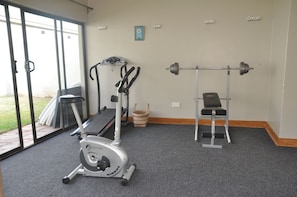 Uma academia com uma bicicleta ergométrica, esteira e rack de agachamento.