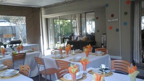 A dining area with tables set for a meal, chairs, and a buffet area in the background. - Coghlan Villa Guest House (Harare)
