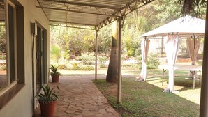 A covered patio area with stone flooring, potted plants, and a white gazebo. - Coghlan Villa Guest House (Harare)