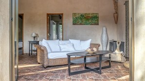 Une pièce chaleureuse avec un canapé en osier, une table basse ronde et un tableau accroché au mur.