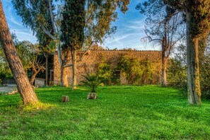 Un bâtiment en pierre avec un toit en tuiles, entouré d’arbres et d’herbe.